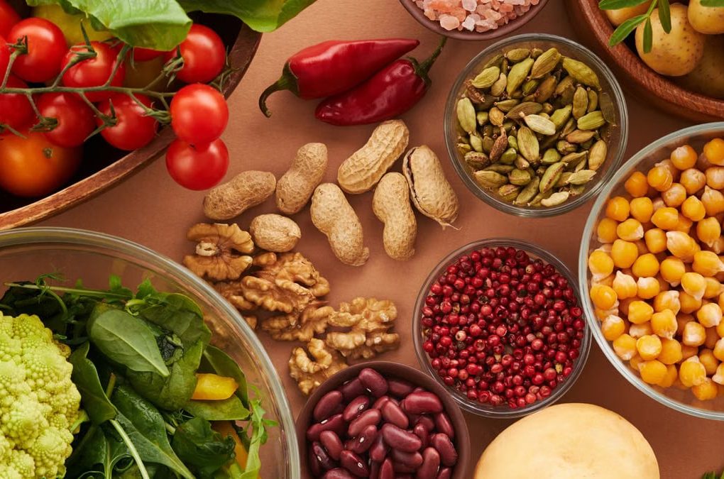Explore a colorful assortment of healthy ingredients, featuring vegetables, nuts, seeds, and spices in a top view layout.